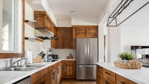A modern kitchen with wooden cabinets, stainless steel appliances, and a white countertop. - Outpost: Granite Canyon at Teton Pines (Wilson)