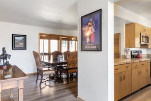 Enjoy meals in the dining area with a wooden table and chairs, kitchen with stainless steel appliances, and a framed poster on the wall.