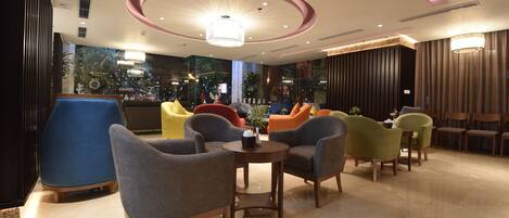 Un espacio lounge moderno con diversas opciones de asientos, incluyendo sofás y sillones, dispuestos alrededor de una mesa central.