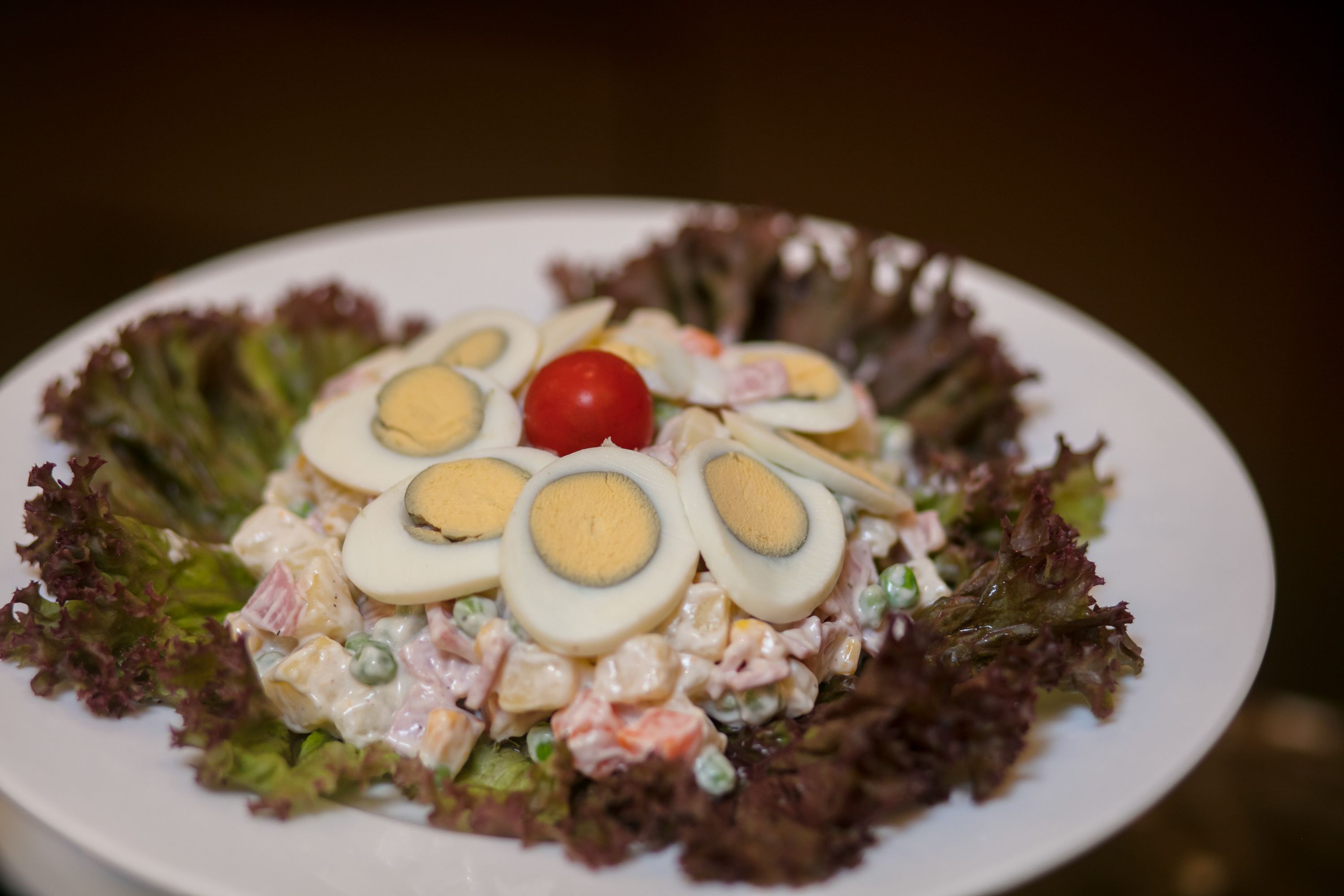 A salad with boiled eggs, tomatoes, and lettuce on a plate.
