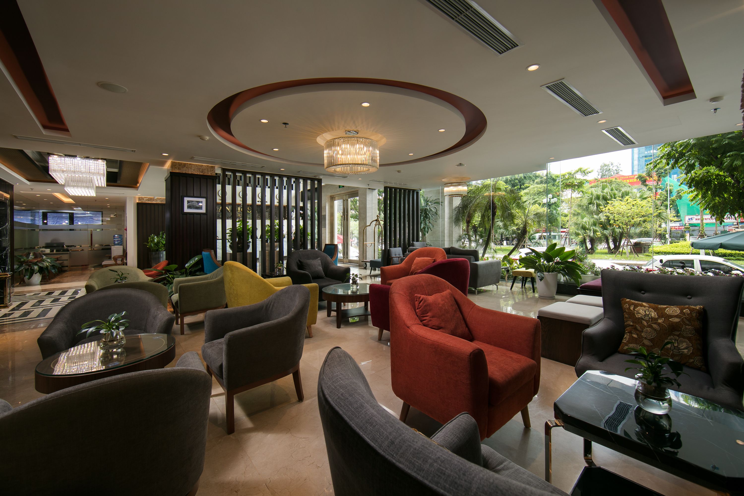 A modern hotel lobby with a variety of seating options, a large chandelier, and a view of the outdoors.