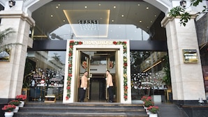 Entrada del Hotel Grandiose con escalones que conducen a la puerta, decorada con guirnaldas festivas y plantas en macetas.