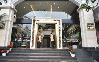 The Grandiose Hotel entrance with steps leading up to the door, decorated with festive garlands and potted plants.