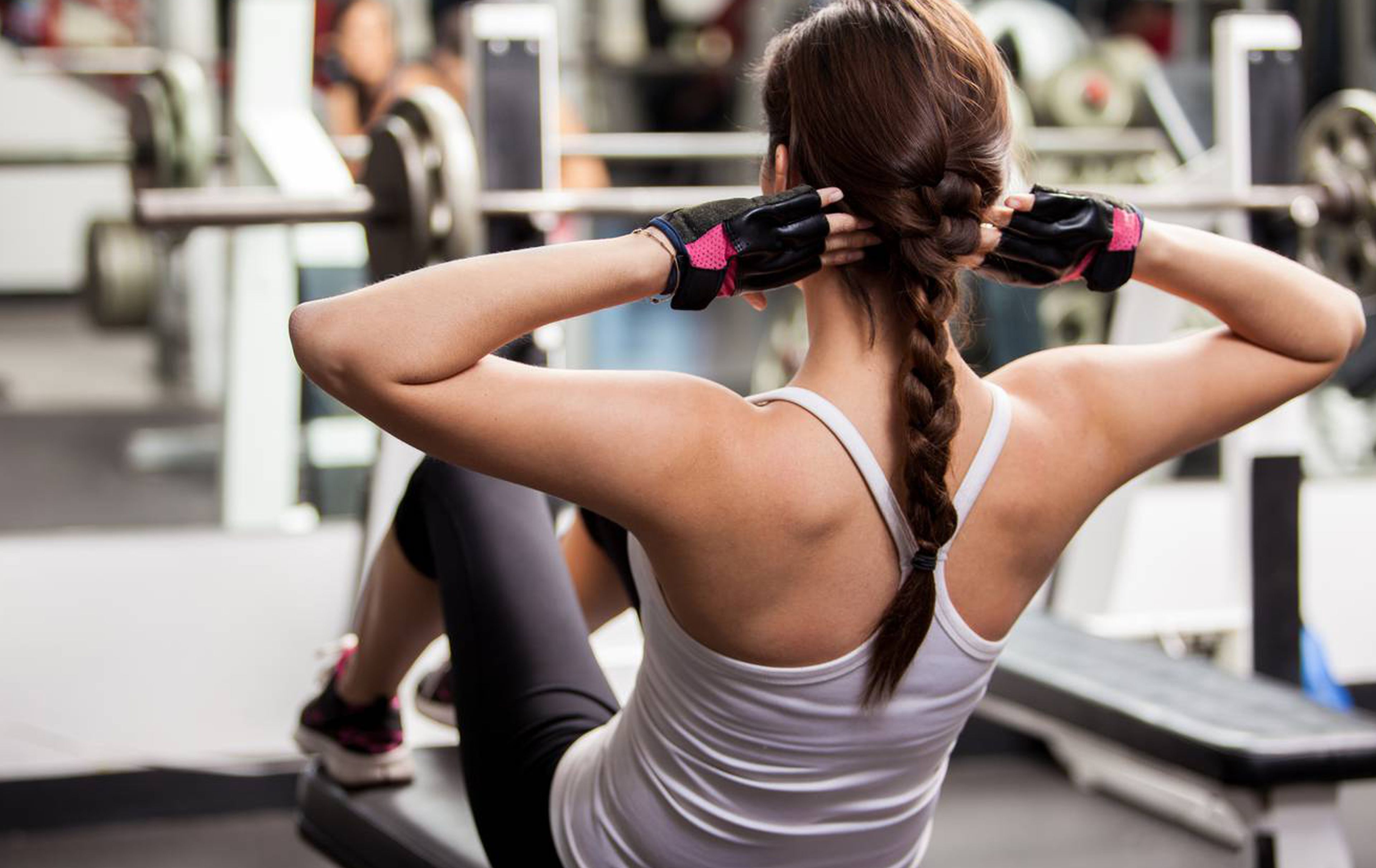 A person exercising in a gym with various equipment in the background.