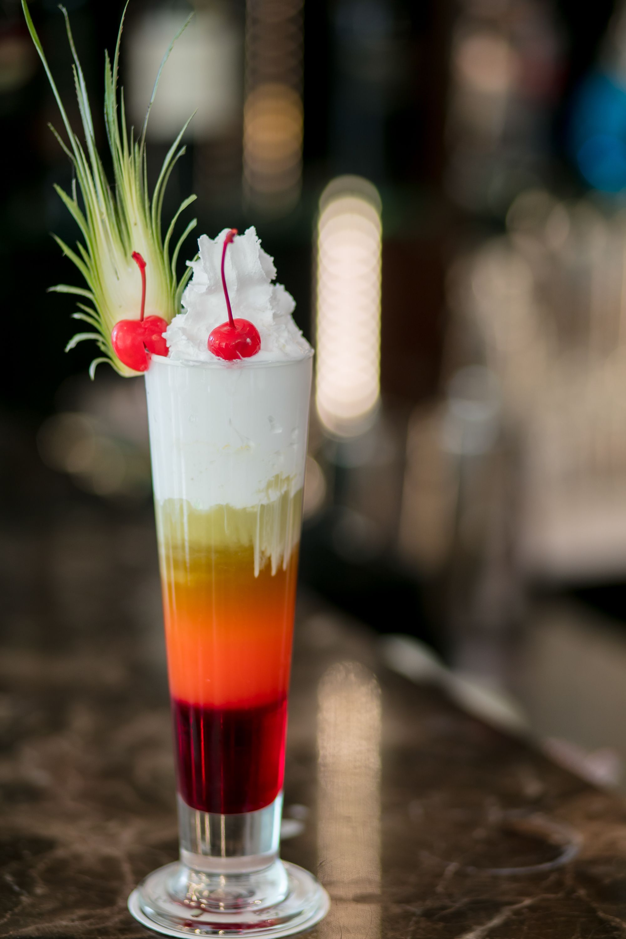 Een gelaagde cocktail in een hoog glas, versierd met garnering.