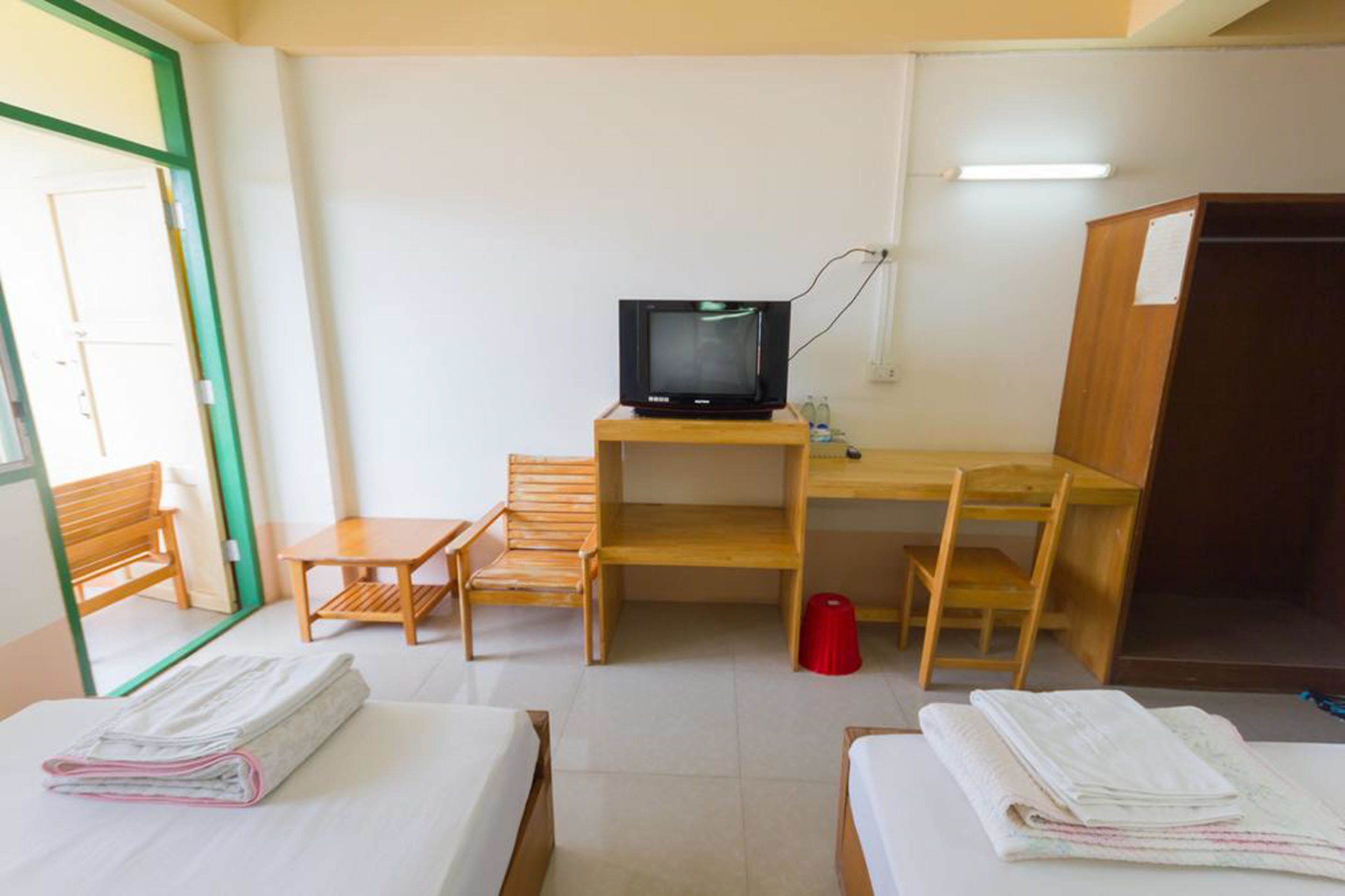 Une chambre d’hôtel avec deux lits, un bureau avec une télévision, une chaise et une petite table.