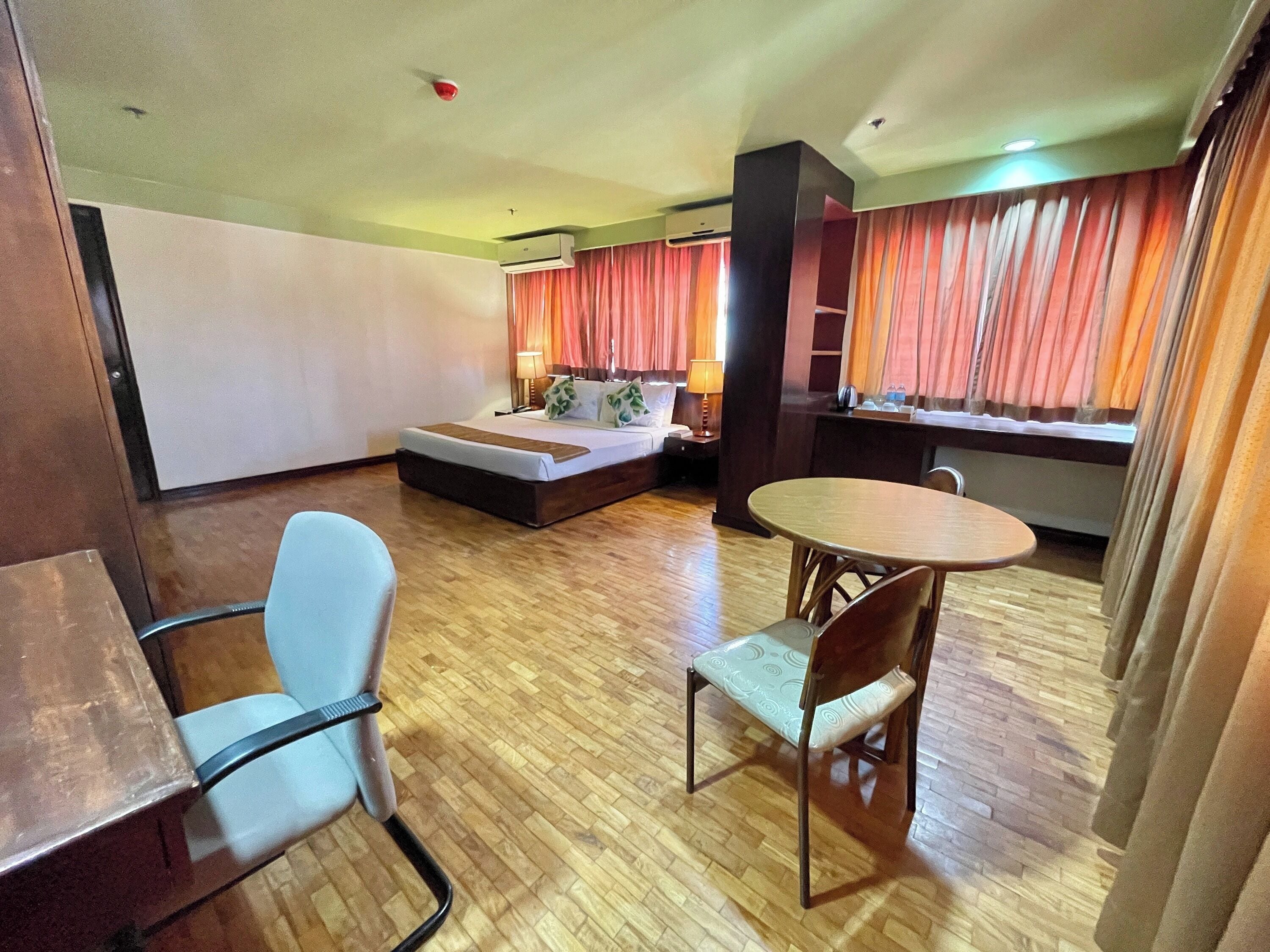 Ein Hotelzimmer mit einem Bett, einem Schreibtisch, einem Stuhl und einem Esstisch.