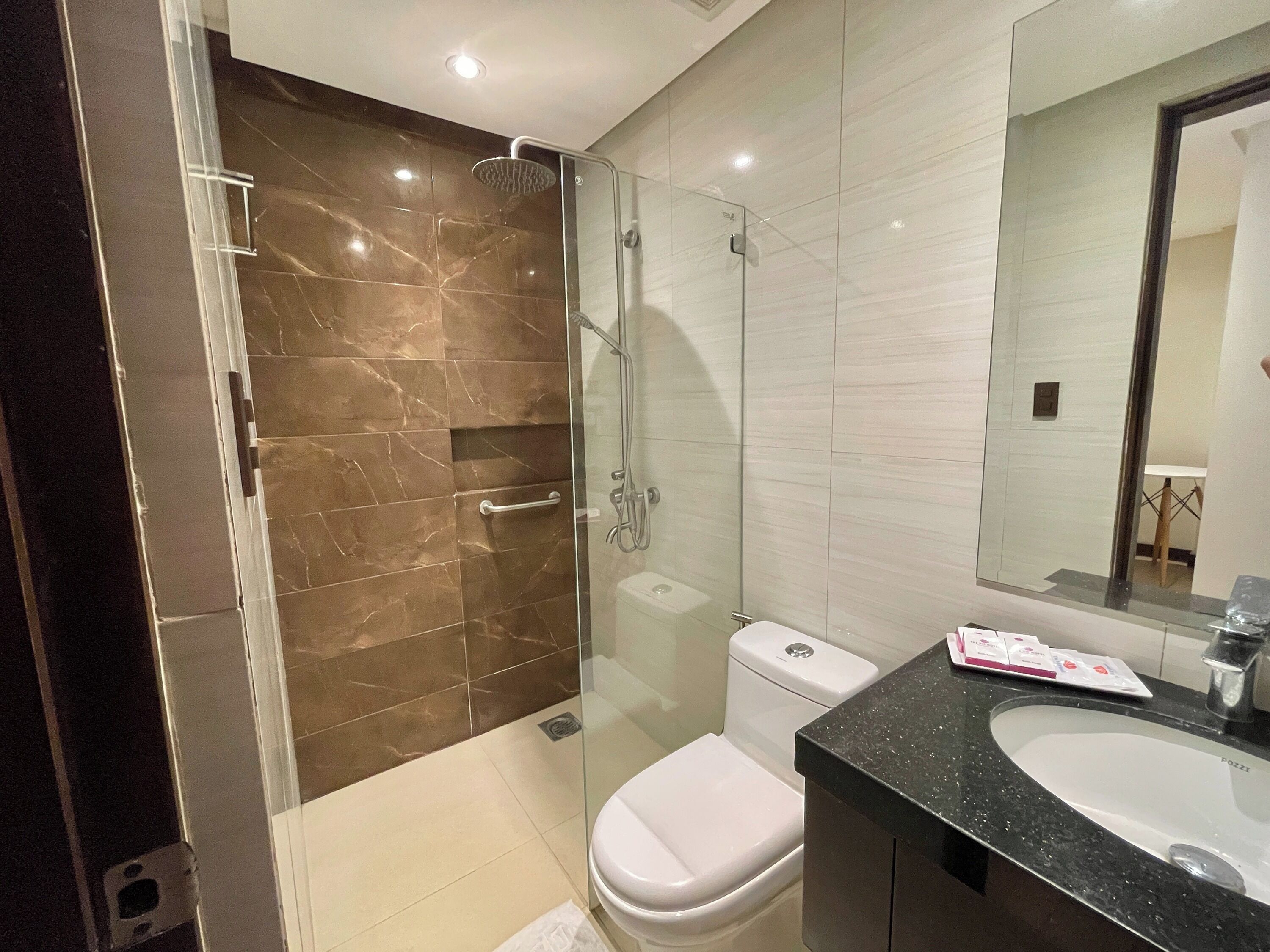 A modern bathroom with a glass-enclosed shower, a white toilet, and a black countertop sink.