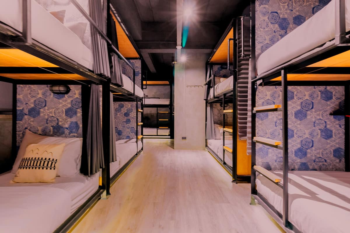 A corridor with bunk beds, patterned wallpaper, and a wooden floor.