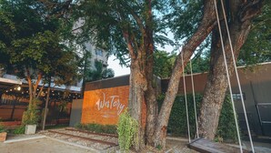 Un patio con una hamaca, árboles, un muro de ladrillo y un cartel que dice 'Westory Design & Postcard'.