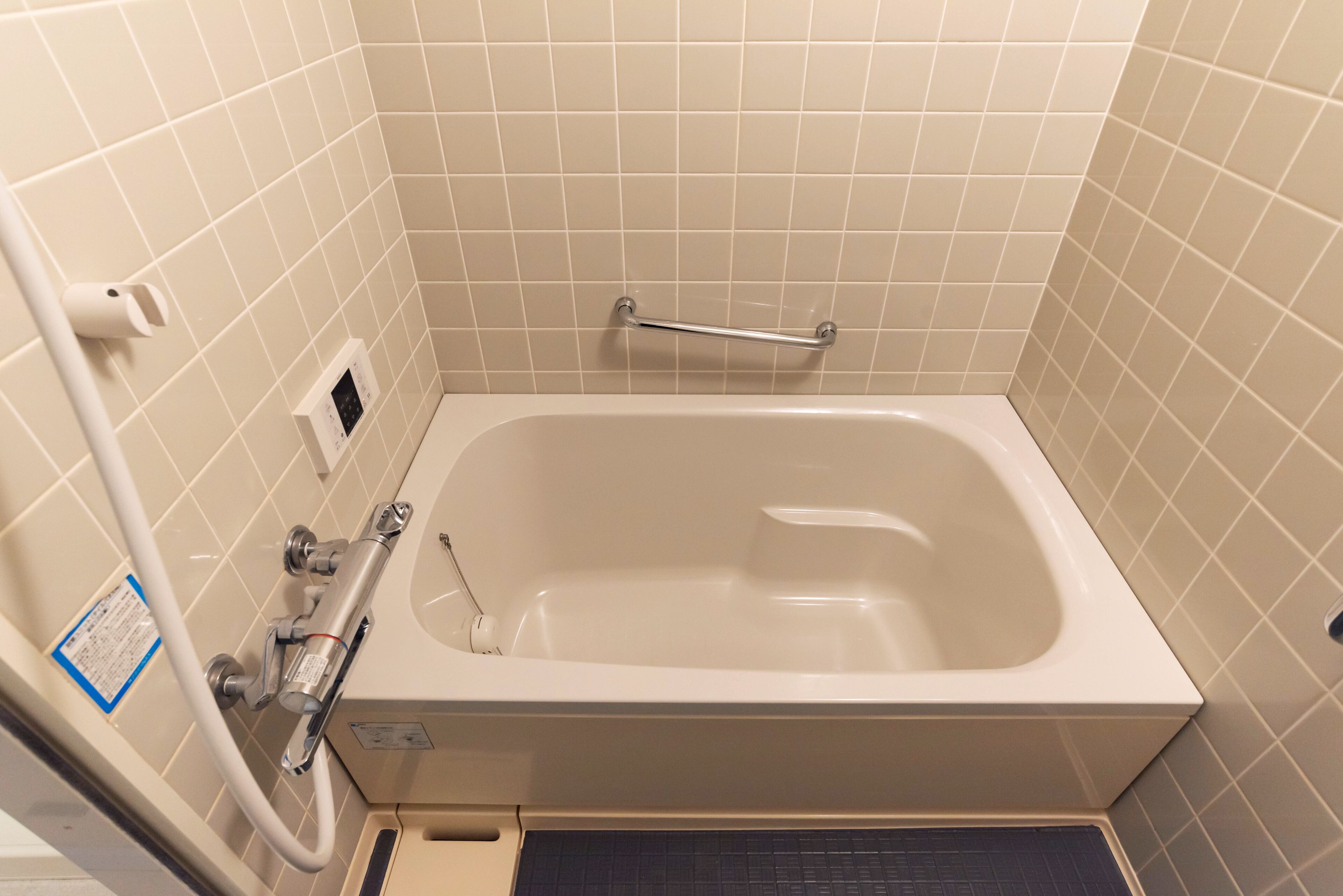 Une salle de bain équipée d’une baignoire, d’une barre d’appui, d’un porte-serviettes et d’un panneau de commande.