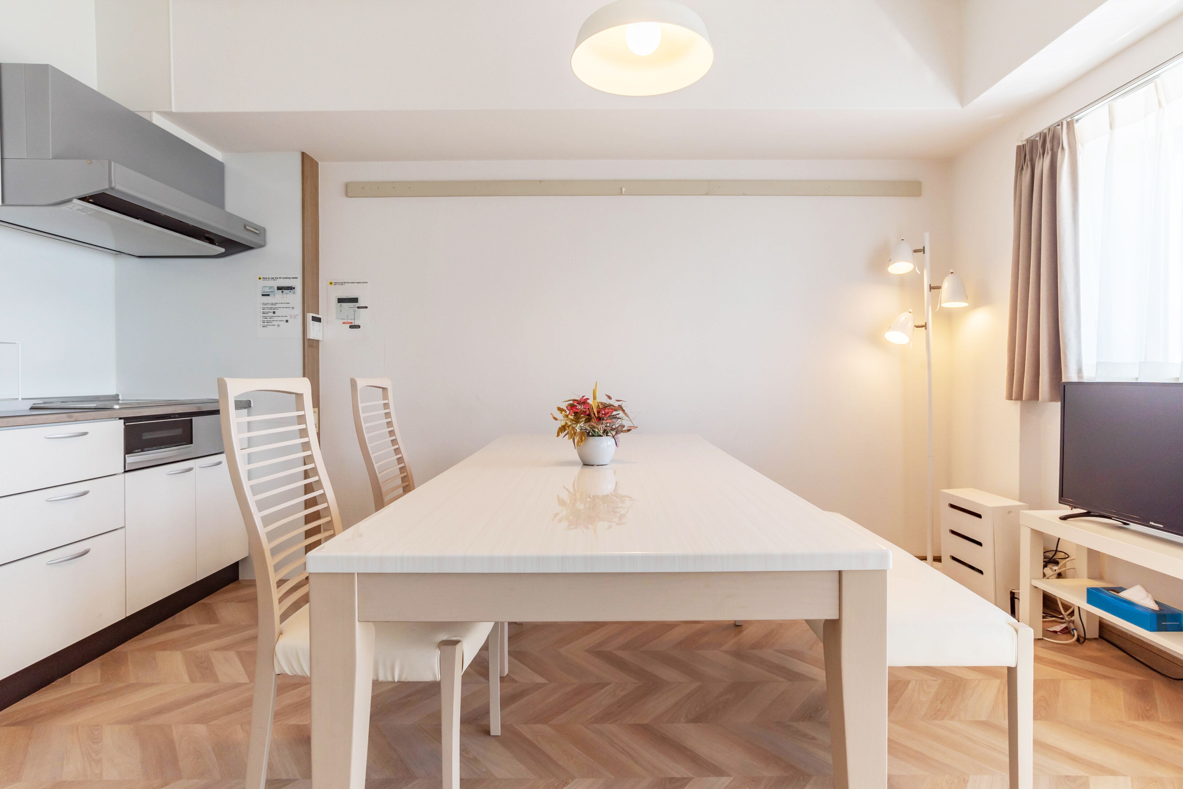 A modern kitchen with white cabinets, a built-in oven, and a stainless steel range hood.