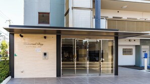 A building entrance with a glass door, a sign reading "Universal Bay," and a tiled wall. - Universal Bay Condominium (Osaka)