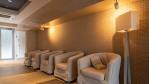 A row of massage chairs against a brick wall with a ceiling light fixture. - Universal Bay Condominium (Osaka)
