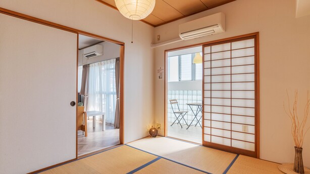A traditional Japanese room with tatami flooring, a shoji screen, and a sliding door. - Universal Bay Condominium (Osaka)