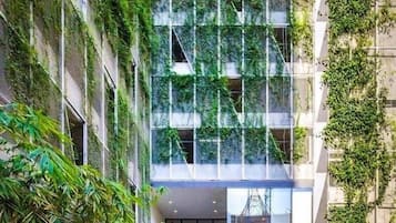 A modern building with a vertical garden facade, a glass atrium, and outdoor seating area.