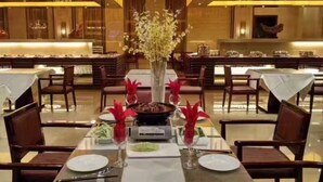 A restaurant with a long table set for dining, featuring a central vase with flowers and red decorative elements. - Ningxia Xigang Airlines Hotel (Yinchuan)