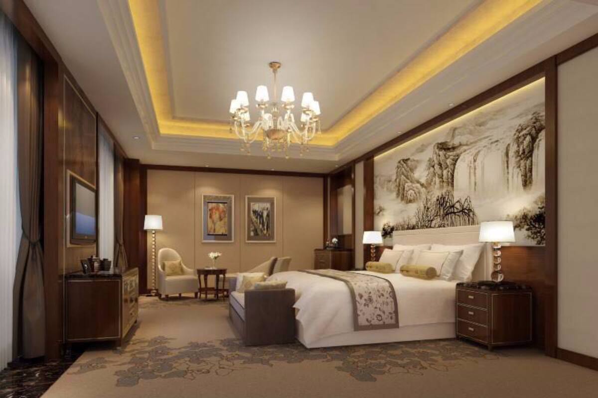 Um quarto espaçoso com uma cama grande, um lustre, um quadro na parede e uma escrivaninha com uma luminária.