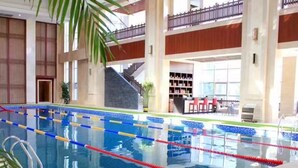 An indoor swimming pool with multiple lanes, surrounded by a green artificial turf area. - Ningxia Xigang Airlines Hotel (Yinchuan)