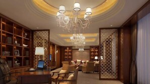 A spacious lobby with a grand chandelier, a leather armchair, a wooden coffee table, and a bookshelf. - Ningxia Xigang Airlines Hotel (Yinchuan)