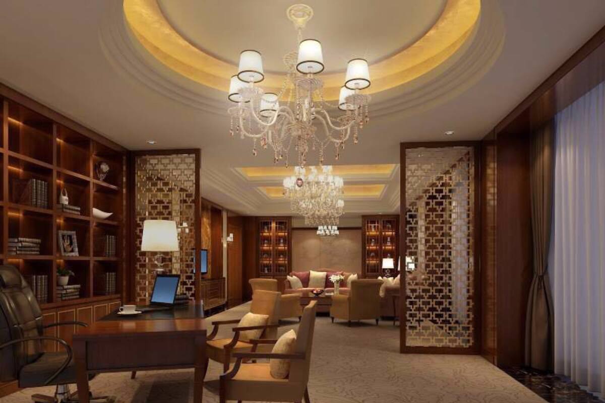 Um hall amplo com um lustre imponente, uma poltrona de couro, uma mesa de centro de madeira e uma estante de livros.