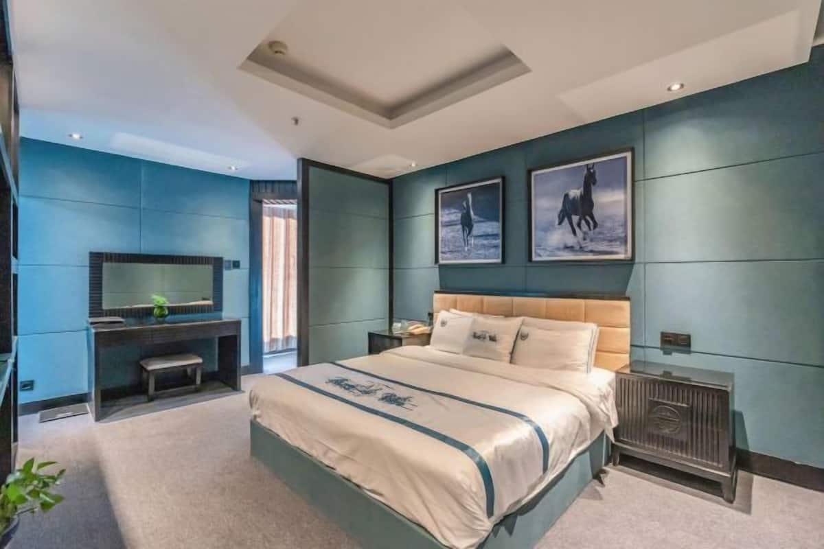 A modern bedroom with a large bed, a desk, and a TV.