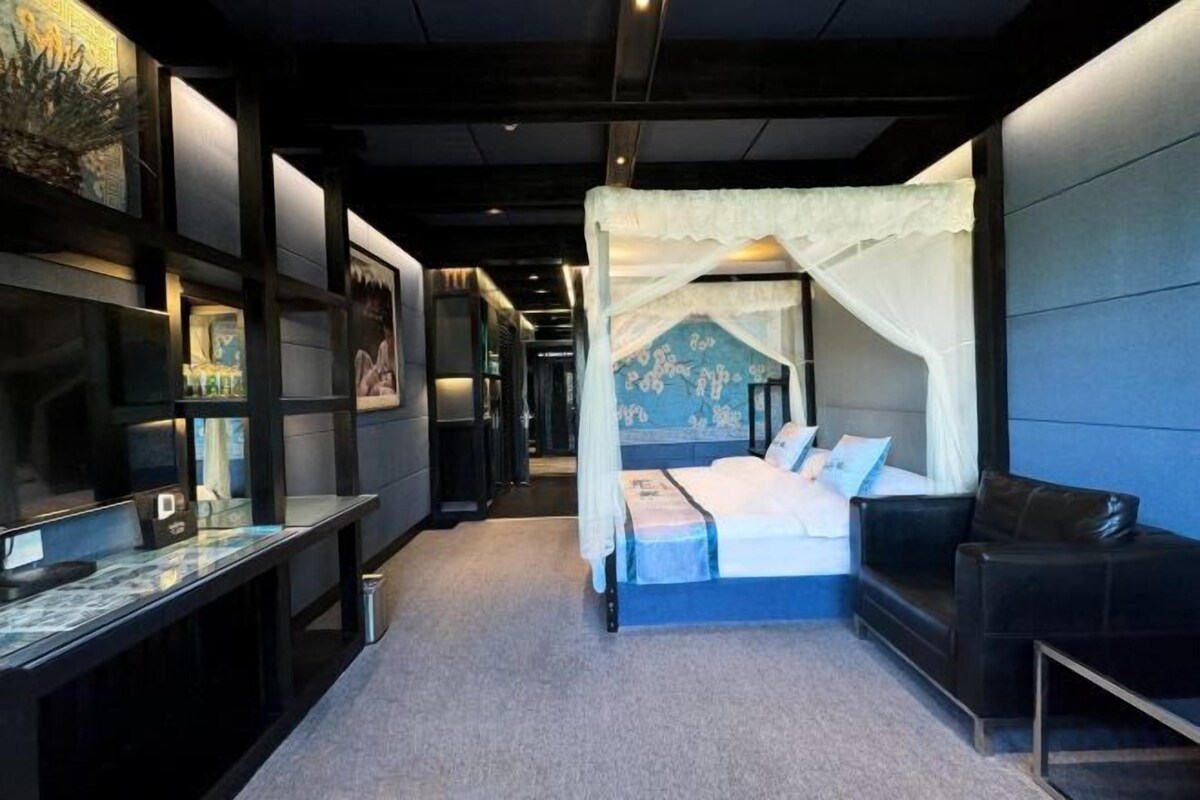 Un dormitorio con cama a dosel, una mesita de noche, una silla y un estante en la pared con objetos.