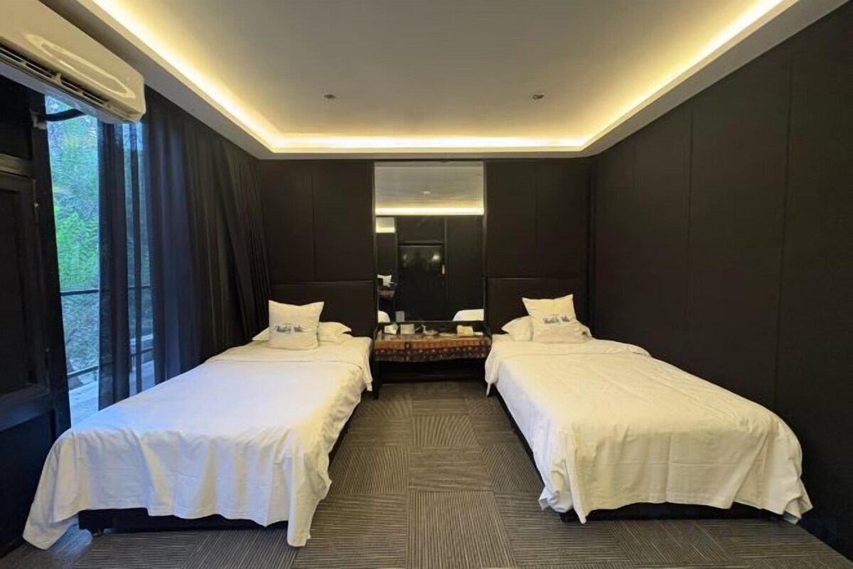 Habitación de hotel con dos camas, un espejo grande y vistas al exterior.