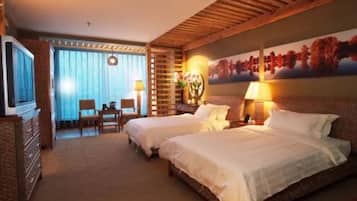 Une chambre d’hôtel avec deux lits, une télévision, un bureau et une fenêtre avec des rideaux.