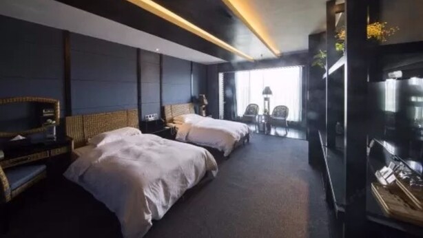 Una habitación de hotel moderna con dos camas, un televisor y un área de estar con sillas y una mesa.