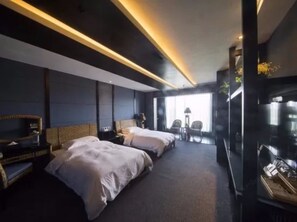 Una habitación de hotel moderna con dos camas, un televisor y un área de estar con sillas y una mesa.