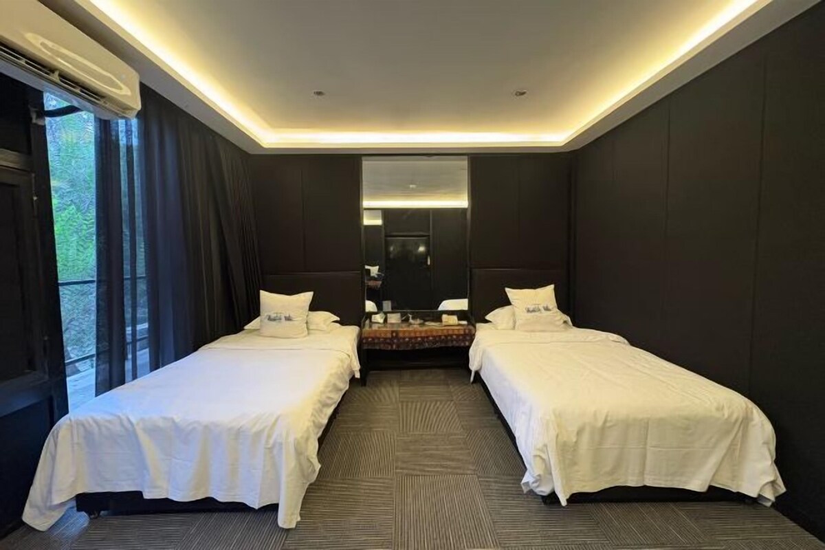Een hotelkamer met twee bedden, een grote spiegel en uitzicht op groen.