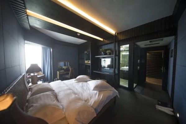 A modern hotel room with a large bed, a desk, and a television.