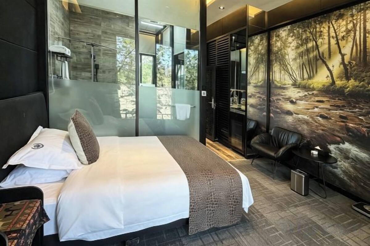 Un dormitorio moderno con una cama grande, una pared de cristal y un mural de un bosque.