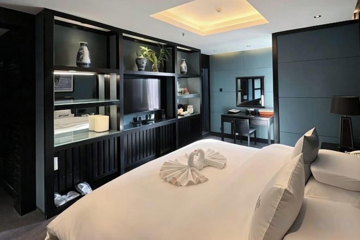 Una habitación de hotel moderna con una cama grande, un televisor de pantalla plana, un escritorio y una zona de estar.