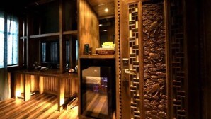 Una habitación con suelo de madera, un banco empotrado, un refrigerador pequeño y un panel decorativo en la pared.