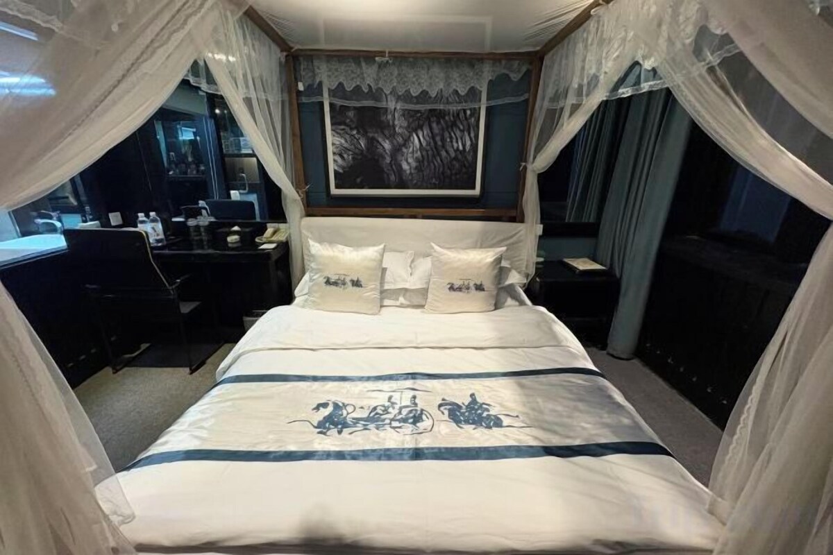 Una cama con dosel, un escritorio y una silla en una habitación de hotel.
