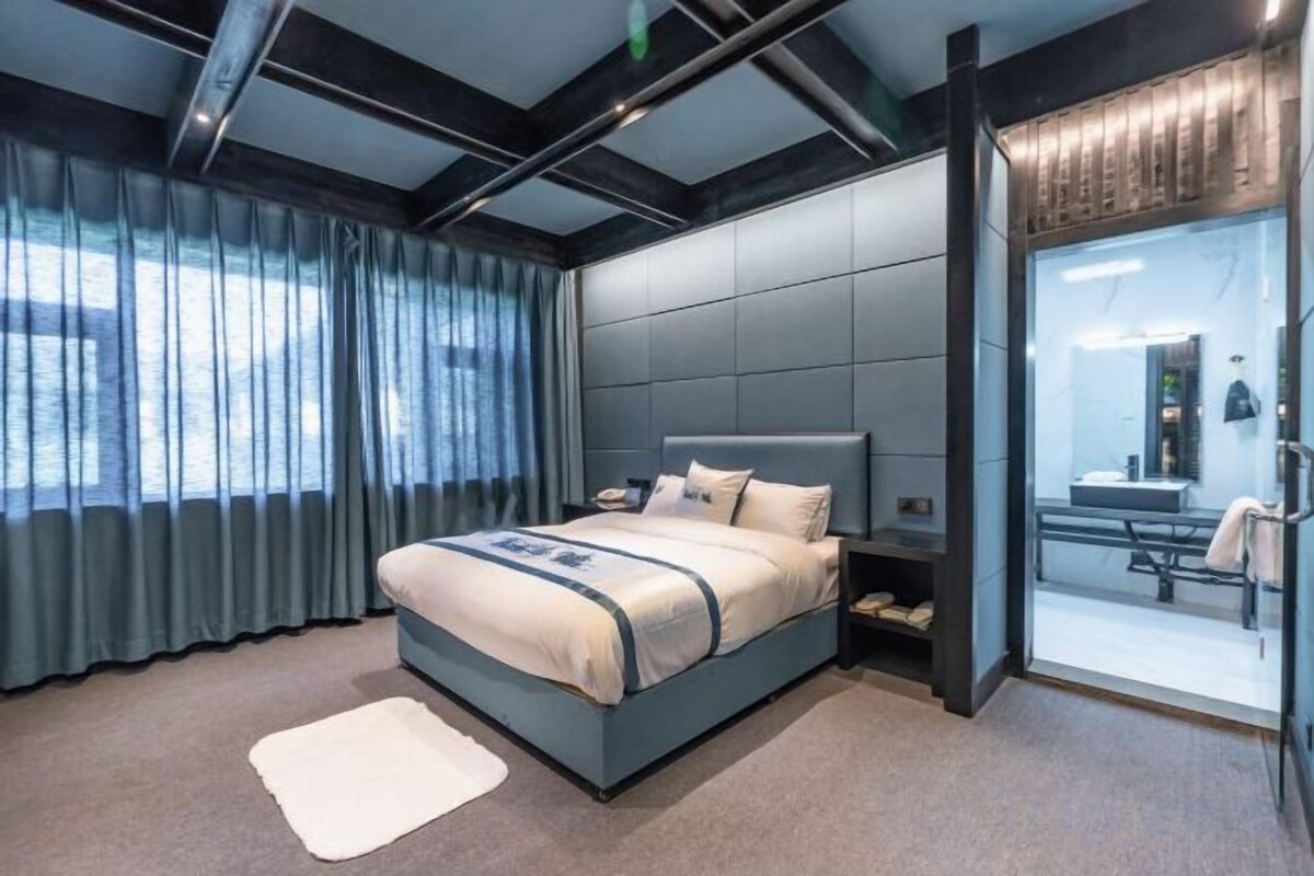 Un dormitorio moderno con una cama grande, una mesita de noche y una puerta de vidrio que da al baño.