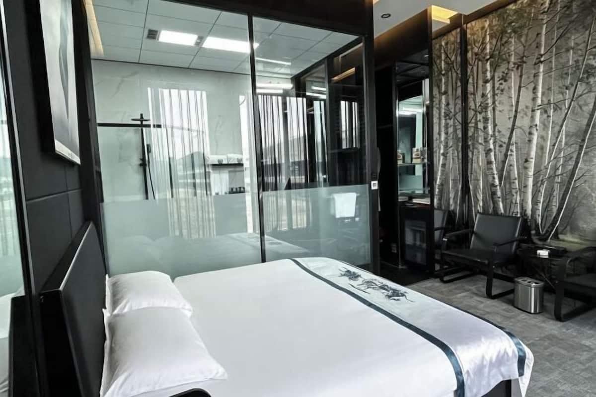 A modern hotel room with a bed, a desk, and a chair.