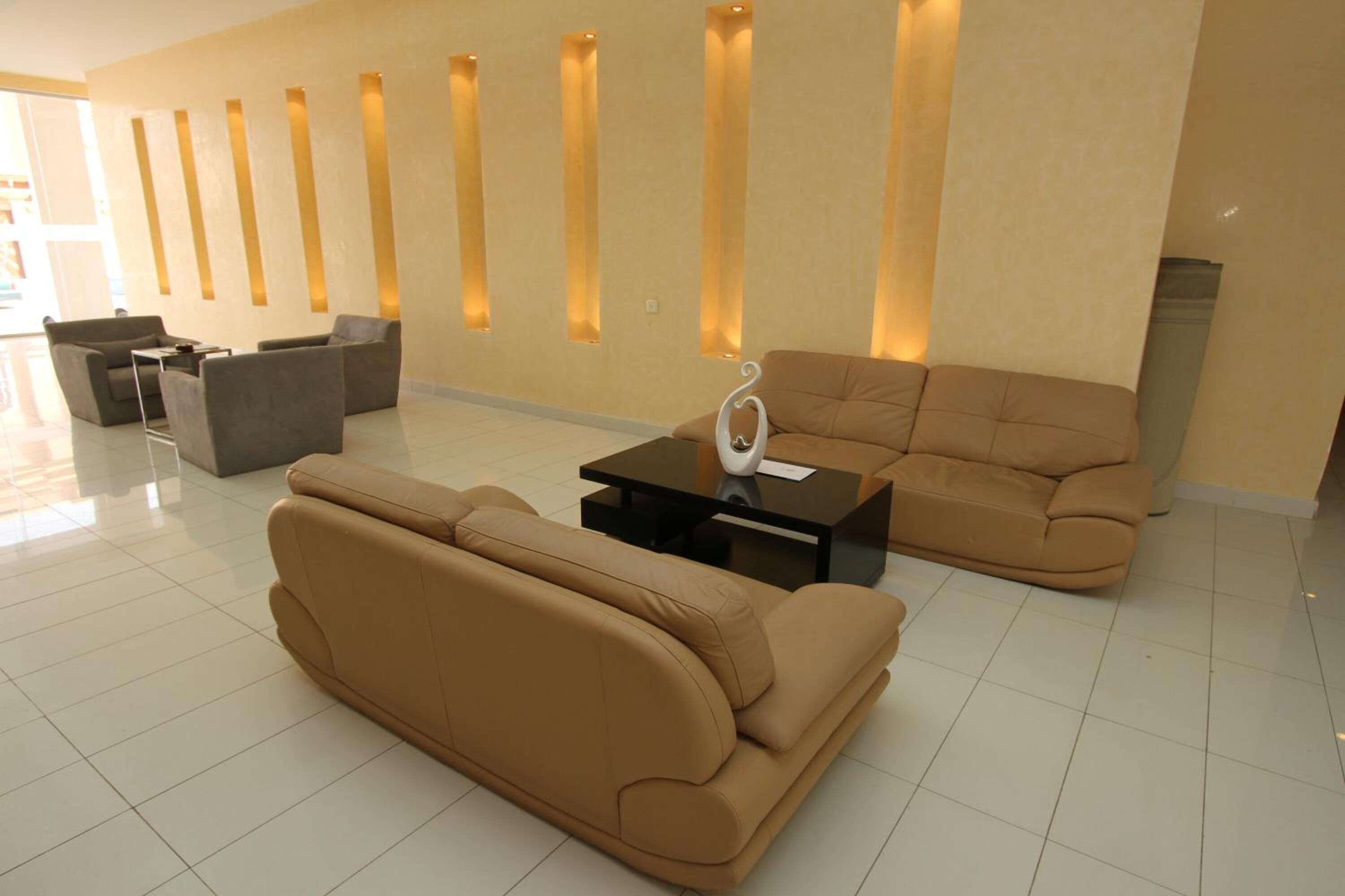 Un hall d’entrée moderne avec un canapé beige, une table basse et un espace salon doté de fauteuils.