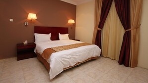 Una camera d'albergo con un letto grande, due lampade sui comodini, un comodino e una finestra con tende.
