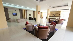 Spaziosa hall con reception, area salotto con divani e televisore a schermo piatto montato a parete.