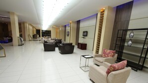Un'ampia hall con soffitto alto, arredi moderni e un'area salotto centrale.