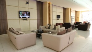Un'ampia zona giorno con una grande TV a schermo piatto montata a parete, diversi divani disposti attorno a un tavolino da caffè e un design d'interni moderno.
