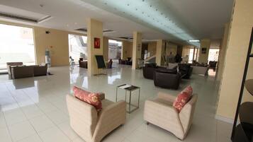 A spacious lobby with a high ceiling, large windows, and a central seating area with sofas.