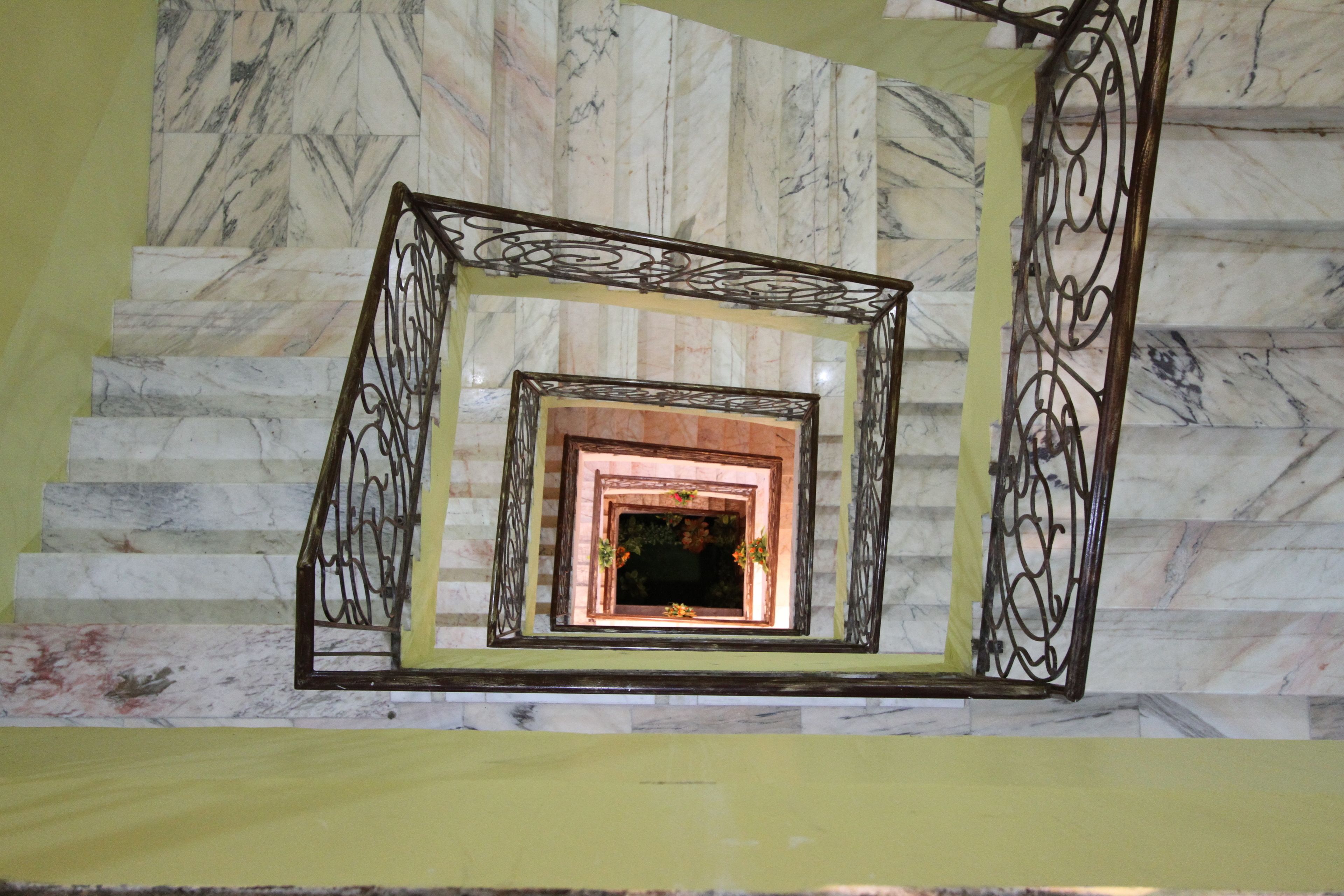 A marble staircase with ornate metal railings and a decorative window at the top.