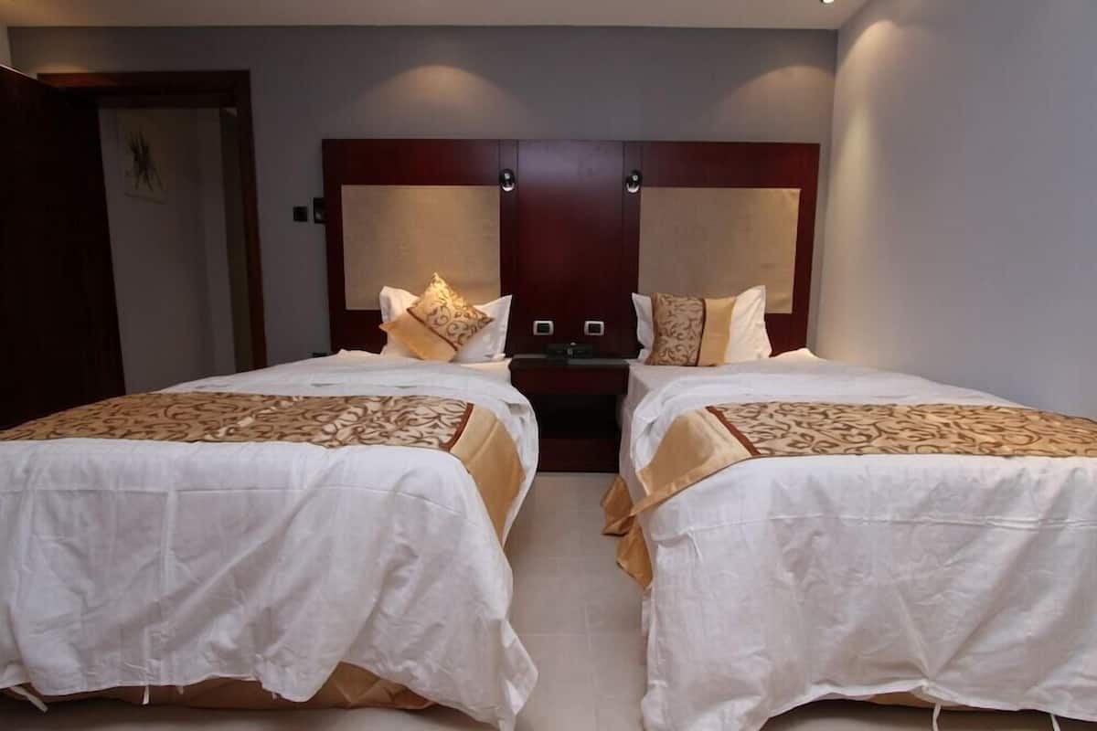 Habitación doble con dos camas, cabecero de madera y una mesita de noche.