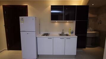 A compact kitchen with a refrigerator, sink, and cabinets.