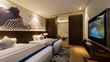A hotel room with two beds, a TV, and a seating area with a table and chairs.