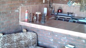 Een rustiek interieur met een bakstenen muur, een opgehangen stierhoofd, een luipaardprintsofa en een klein houten krukje.